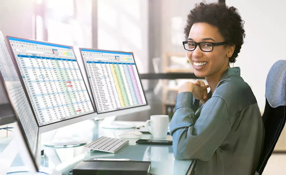 female working on 3 desktop screens